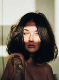 a woman with a tattoo on her arm posing for a photo in front of a mirror