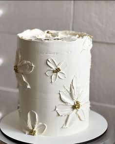 a white cake with flowers on it sitting on a plate in front of a tiled wall