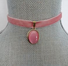 "Lovely pink velvet ribbon is threaded with a gold slider bail, linked with an oval gold and pink pearl cabochon focal.   The velvet ribbon closes at 13\" on first link and with the matching extension chain will adjust an additional 2\". There is a hook closure on the choker. The cabochon focal measures 3/4\" X 5/8\". All of my jewelry items come boxed, and ribbon tied and tagged for easy gifting." Adjustable Pink Oval Jewelry, Pink Adjustable Oval Jewelry, Adjustable Oval Pink Jewelry, Choker Velvet, Fabric Choker, Pink Choker Necklace, Pink Velvet Ribbon, Velvet Accessories, Pink Choker