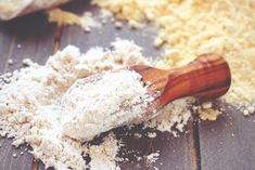 a wooden spoon filled with powdered sugar on top of a wood table next to other ingredients