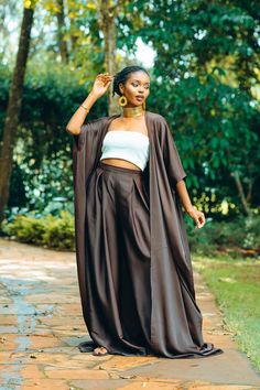 Make a statement with our Brown Palazzo Pants & Kimono Set. This stunning ensemble features elegant brown palazzo pants paired with a matching kimono, exuding timeless sophistication. The palazzo pants offer a flowing silhouette and a convenient pocket detail, while the kimono adds a touch of grace with its flowing design. Wear them together for a coordinated look that exudes class and refinement, or mix and match with other pieces in your wardrobe for versatile styling options. From daytime outings to evening events, this versatile set effortlessly transitions from casual to formal, ensuring you look chic and polished wherever you go. - This palazzo set is made from a light and breathable silky fabric making it a perfect addition to your summer fashion style. - The model is wearing an XL. Flowy Pants Outfit, Chiffon Palazzo Pants, Flowy Fashion, Kimono Pants, Brown Kimono, Kimono Set, Elegant Kimono, Jazz Fest, Palazzo Set