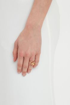 a woman's hand with a gold ring on top of her left hand, against a white background