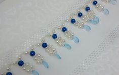 a white table topped with lots of blue and white beads