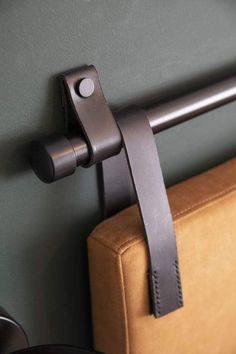 a brown leather chair with a black handle on it's arm and a gray wall in the background