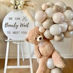 a brown teddy bear sitting on top of a white chair next to a bunch of balloons