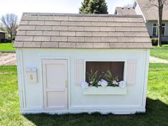 a white dog house with flowers in the window