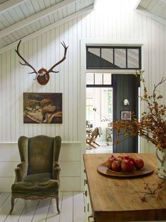 a wooden table topped with apples next to a vase filled with flowers and antlers