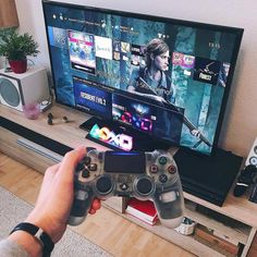 a person holding a video game controller in front of a flat screen tv with games on it