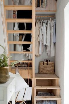 an open closet with clothes hanging on the wall and stairs leading up to it's second floor