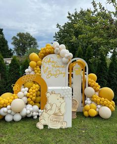 a winnie the pooh themed birthday party with balloons and decorations on grass in front of trees