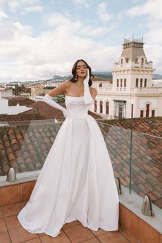 a woman standing on top of a roof wearing a white dress