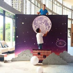 a man standing on top of a giant paper moon in the middle of a room