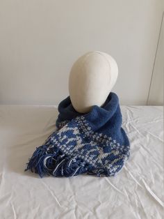 a white ball sitting on top of a blue blanket next to a hat and scarf