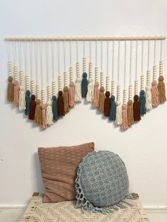 a wall hanging with tassels on it next to a pillow and throw pillow