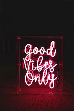 a neon sign that says good vibes only on the floor in front of a black background