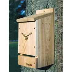 a wooden birdhouse with an eagle on it's face is attached to a tree