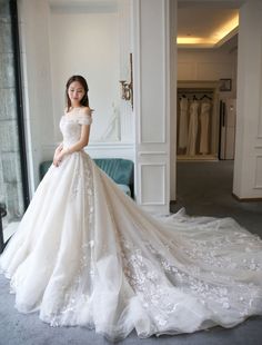 a woman in a wedding dress standing next to a couch and looking at the camera