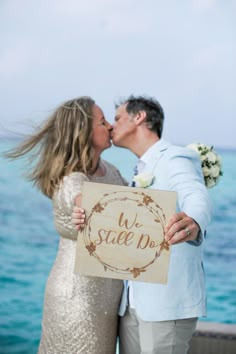 a man and woman kissing while holding a sign