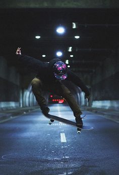 a man riding a skateboard down the side of a road in a dark tunnel