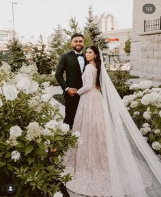 a bride and groom standing in front of white flowers