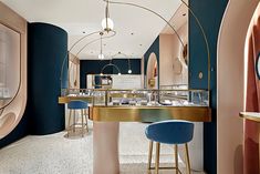 the interior of a restaurant with blue and pink walls, gold accents and bar stools