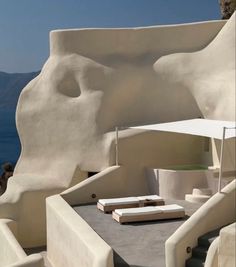 a white building with steps leading up to it and an ocean view in the background