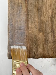 a person holding a paintbrush over a wooden wall