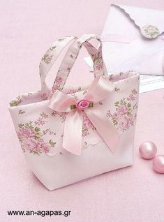 a pink flowered bag sitting on top of a table next to pearls and an envelope