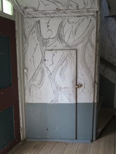 an old door in the corner of a room with wood flooring and painted walls