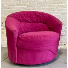 a pink chair sitting in front of a white brick wall