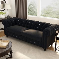 a living room with a black couch and two chairs in front of a large window