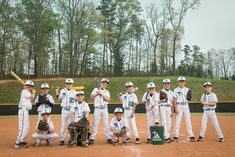 a group of young boys standing on top of a baseball field wearing white and blue uniforms