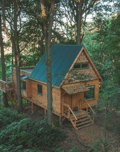 a small cabin in the woods with stairs leading up to it's second floor