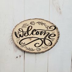 a wooden sign that says welcome hanging on the side of a white door with wood planks