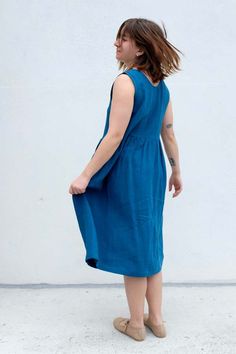 This linen dress features a round neck wide straps and a buttonhole at the front. it also has gathered details at the waist for a voluminous effect and a convenient right chest pocket. lightweight and made of 100% oeko tex certified linen it's perfect for staying cool on those scorching summer days.    details:    -  100% oeko tex certified linen  -  made in montreal canada.    gabrielle is 5'5" bust 35" waist 29" hips 36" wearing a size s  styled with small lot mary janes    about the brand:    a pioneer in quebec fashion the brand was founded in 2002 by montreal designer eve gravel. her creations embody a contemporary colourful and versatile aesthetic offering throughout each collection a few bold pieces that elegantly punctuate the minimalist and timeless character of eve gravel. each s Linen Dress With Gathered Waist For Daywear, Casual Linen Dress With Gathered Waist, Quebec Fashion, Contemporary Clothes, Versatile Aesthetic, Rose Lily, Easy Tiger, Blue Flats, Montreal Canada