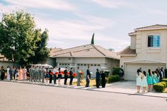 a group of people standing in front of a house on the side of the road