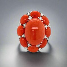 This exquisite ring boasts a striking combination of coral and diamonds, set in 18K white gold. Its bold and beautiful design is perfect for making a statement. The luxurious materials and expert craftsmanship make it a timeless piece to treasure for years to come. Jewelry Style: RingMetal Type : 18K White GoldWeight : 20.76 gramsRing Size : 7Estate - pre-ownedMeasurement : 30 mm x 25 mmCoral Shape : OvalCoral Weight : 25.02 ctQuantity : 9Diamond Shape : RoundWeight : 1.25 cttwColor : IClarity : SI2 This is sold as an estate piece, all weights are estimates. Elegant Multi-stone Orange Rings, Elegant Orange Multi-stone Rings, Elegant Oval Coral Rings, Elegant Coral Ring Jewelry, Elegant Coral Rings For Anniversary, Elegant Coral Oval Rings, Coral Elegant Wedding Rings, Elegant Coral Wedding Rings, Elegant Orange Diamond Ring With Gemstone