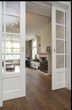 an open door leading to a living room with wood floors and white furniture in the background