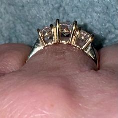 a woman's hand holding a ring with three small diamonds on the middle of it