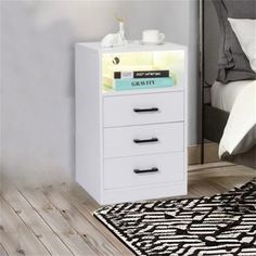 a white night stand with three drawers and a rug on the floor in front of it