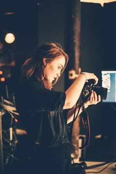 a woman holding a camera in front of a monitor