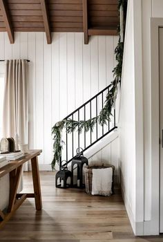 a wooden table sitting next to a stair case in a room with white walls and wood floors