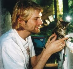 a man holding a kitten in his right hand