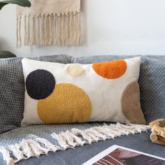 a couch with a decorative pillow on top of it next to a book and plant