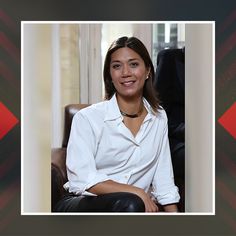 a woman sitting in a chair wearing a white shirt and black leather pants is smiling at the camera