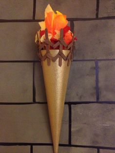 there is a gold cone with orange flowers in it on the brick wall and floor