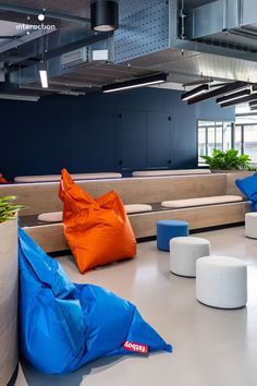 blue and orange bean bags are on the floor in an office lobby with white stools