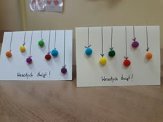 two cards with different colored balls hanging from them on a table next to each other