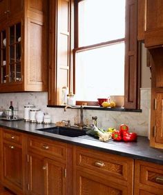 a kitchen filled with lots of wooden cabinets and counter top space next to a window