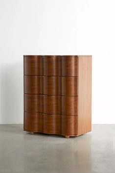 a tall wooden dresser sitting on top of a cement floor next to a white wall